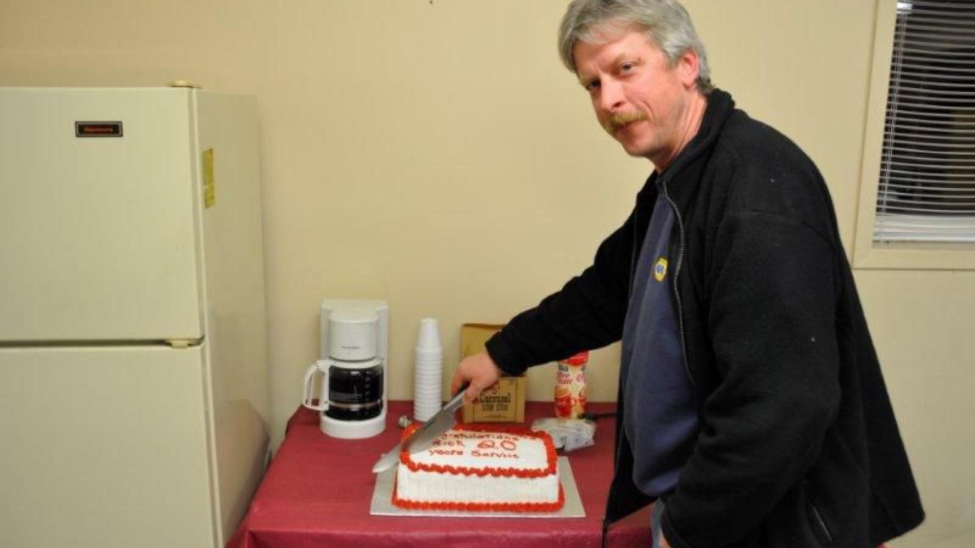 Rick Pecaskie cutting a cake celebrating 20 years of service