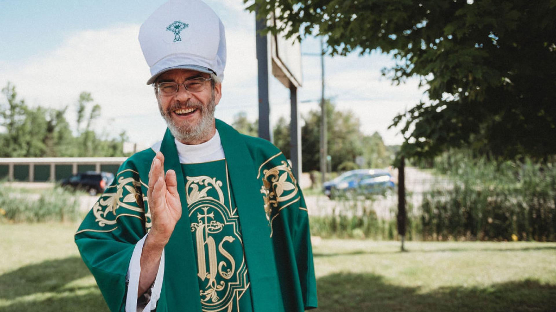 an elderly man in green, white and gold clergy robes