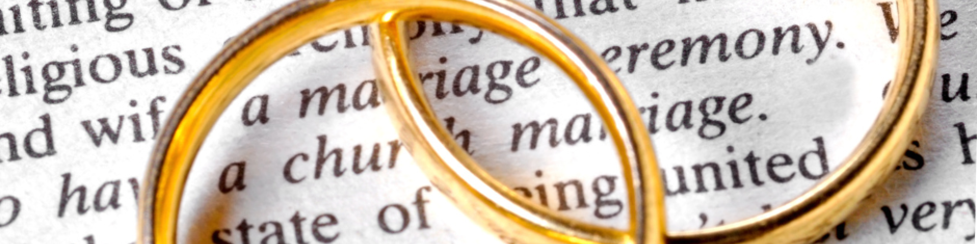 rings sitting on top of a dictionary page with the definition of marriage