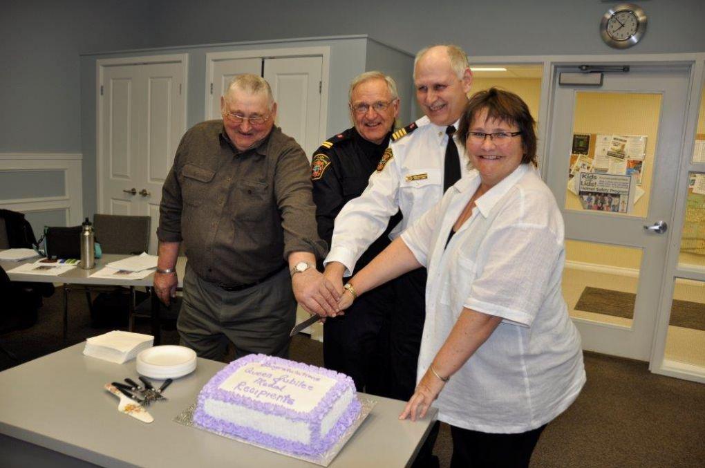Four people cutting a cake together at an indoor celebration.
